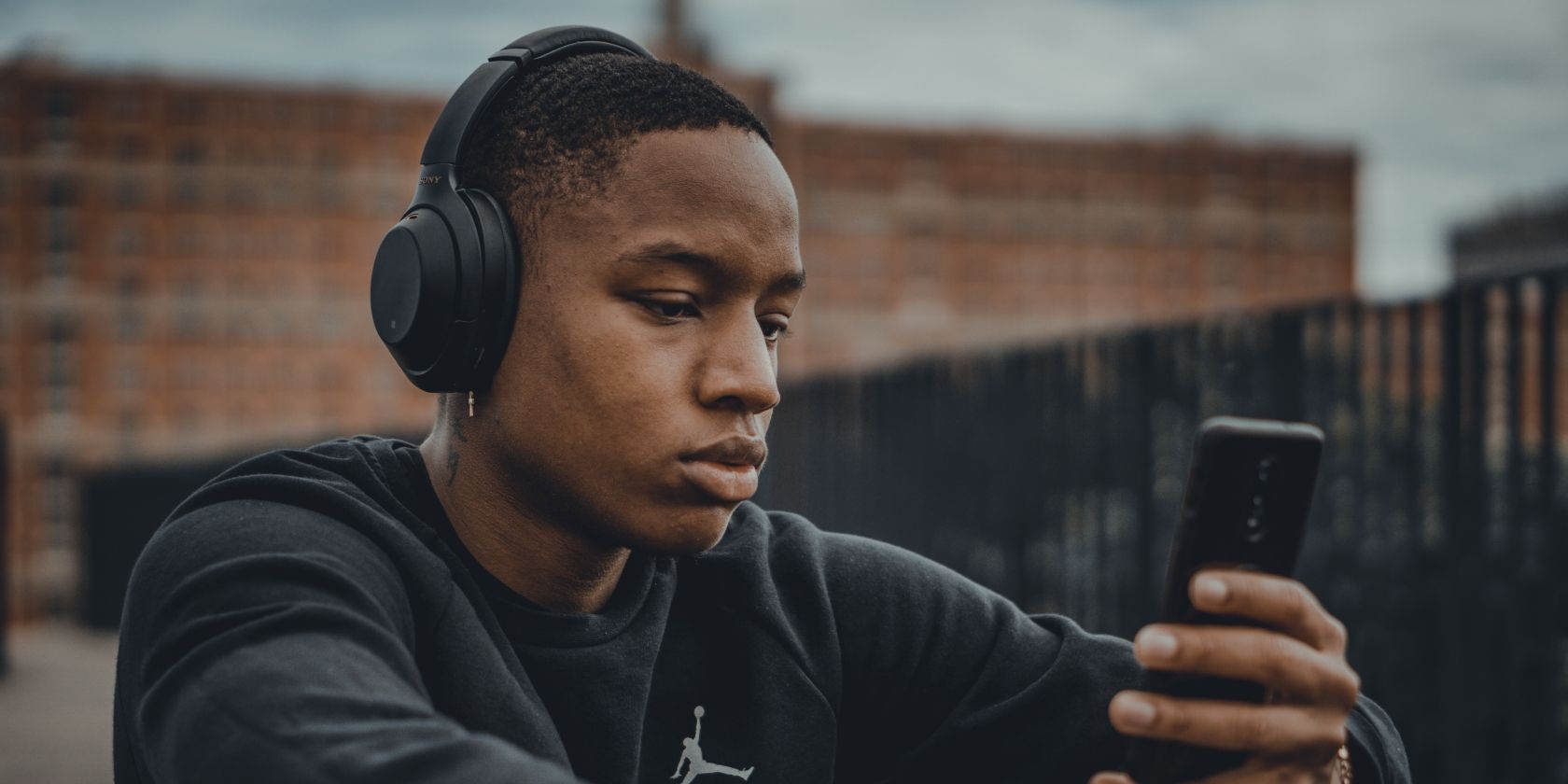 /bc/images/young-man-listening-to-music-on-mobile-phone-with-headphones-on.jpg