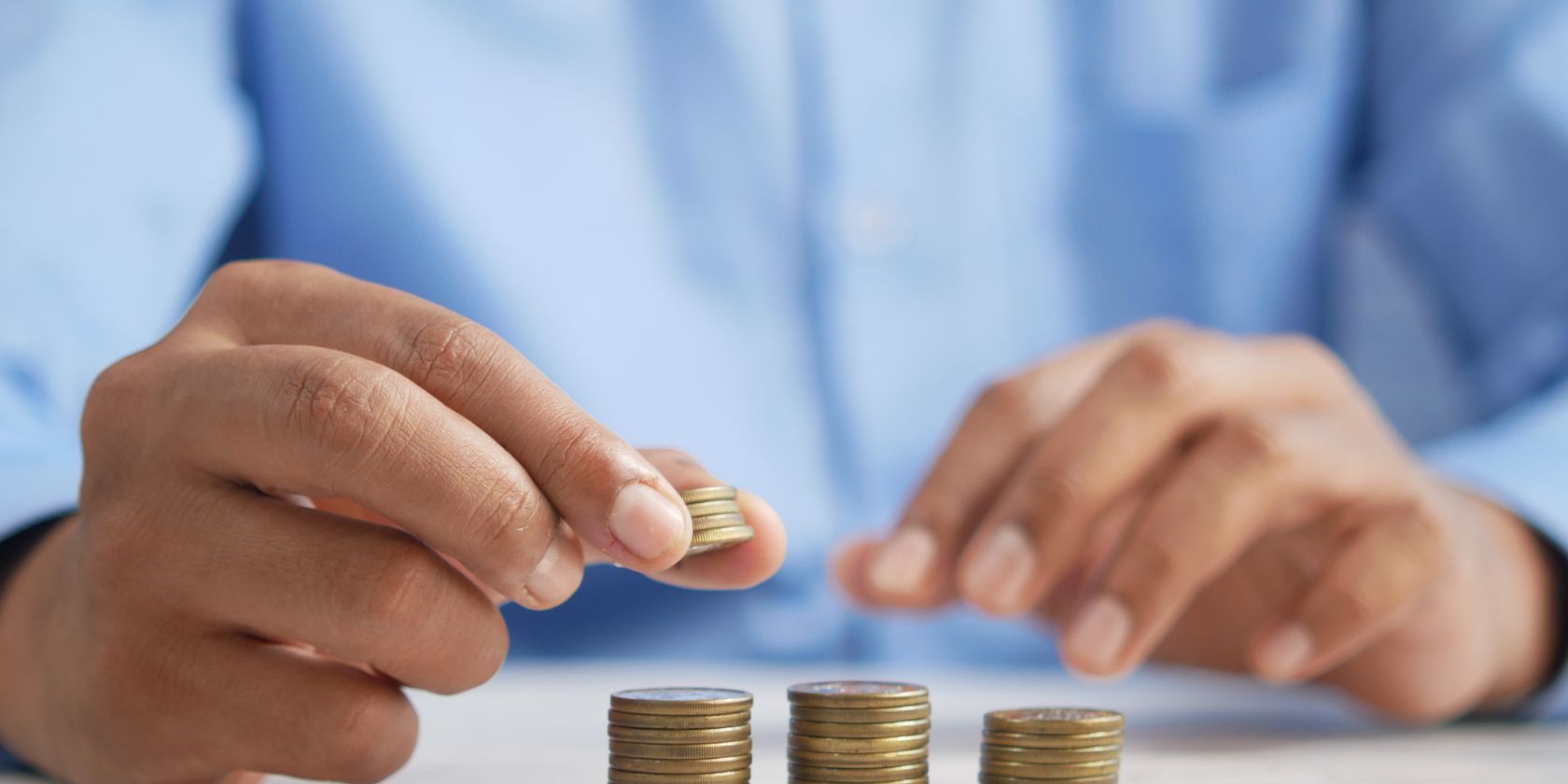 /pt/images/a-person-stacking-coins-on-top-of-a-table.jpg