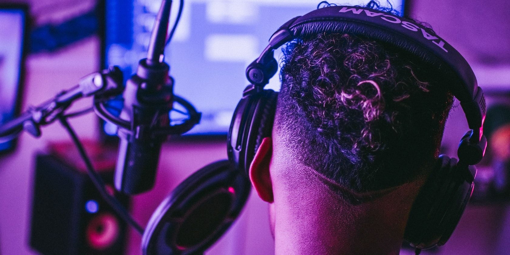 /pt/images/a-person-wearing-headphones-next-to-a-microphone-and-pc-screen.jpeg