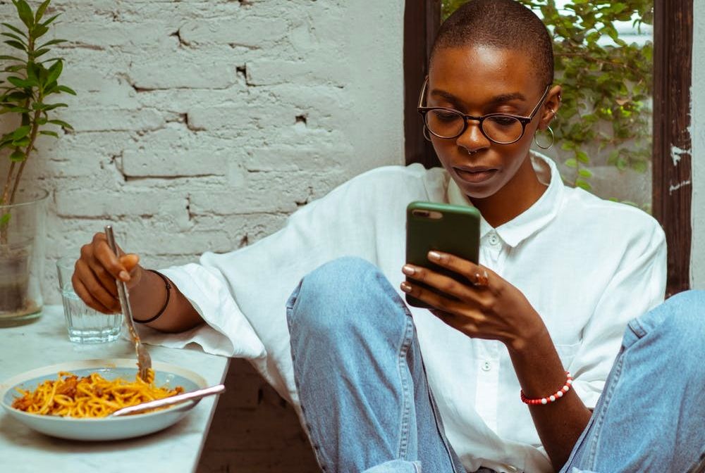 /pt/images/a-woman-eating-pasta-while-looking-at-a-phone.jpg