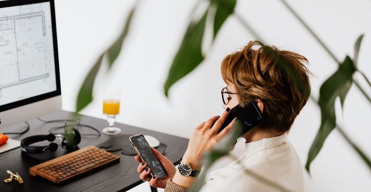 /pt/images/image-of-a-woman-in-front-of-a-computer-holding-a-phone-while-talking-on-another.jpg