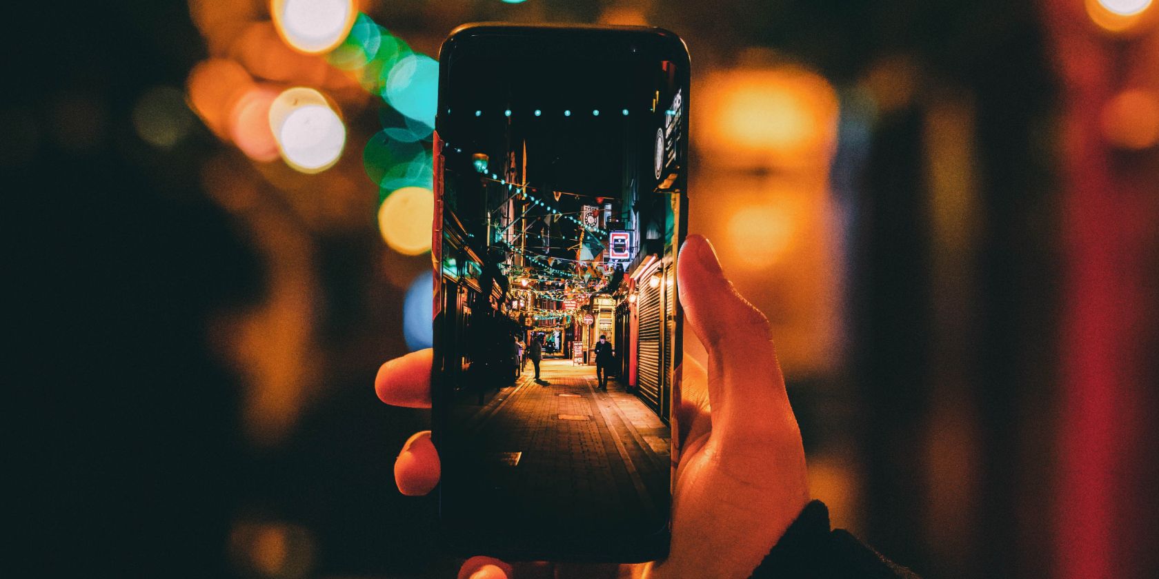 /pt/images/person-holding-phone-taking-picture-of-lights-at-night.jpg