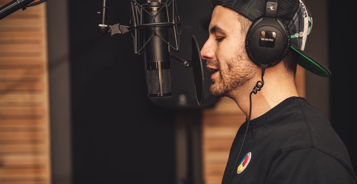 /pt/images/person-singing-microphone-pop-shield-headphones.jpg