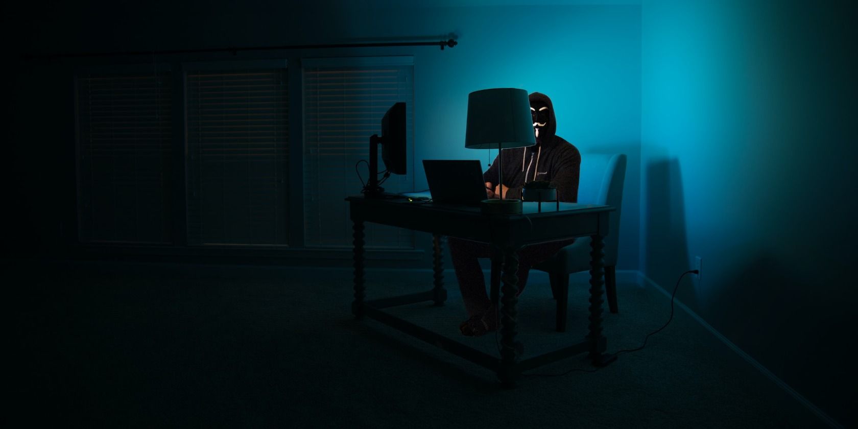/sv/images/man-in-hacker-mask-sitting-at-desk-in-dark-room.jpg