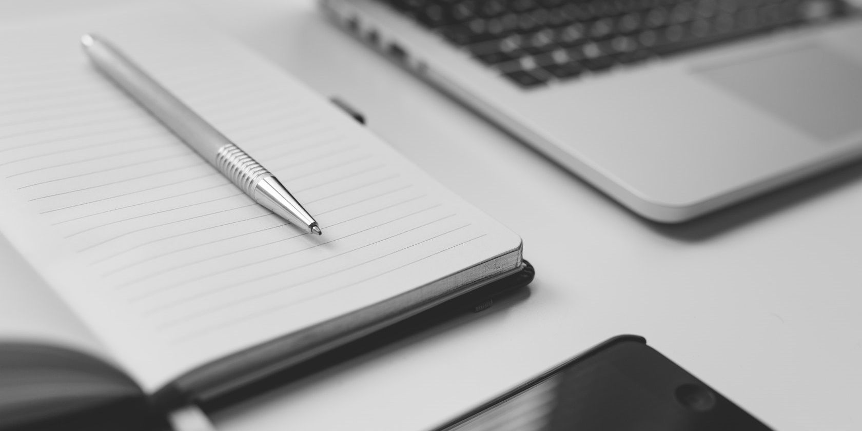 /sv/images/silver-pen-on-notebook-beside-laptop.jpg