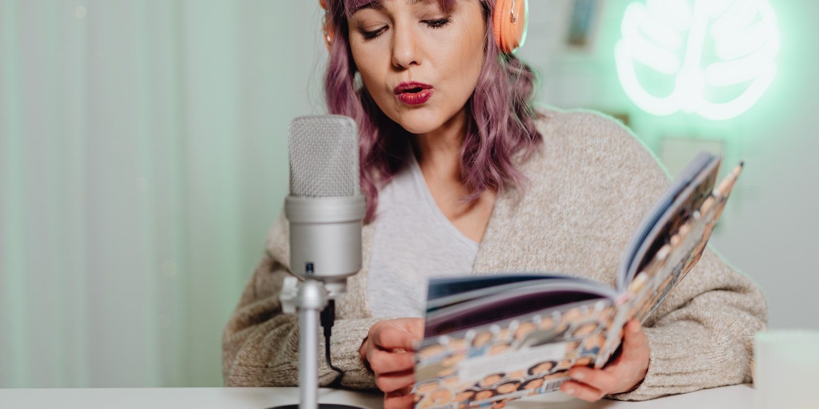 /th/images/a-woman-talking-into-a-microphone-while-reading-a-book.jpg /th/images/a-woman-talking-into-a-microphone-while-reading-a-book.jpg