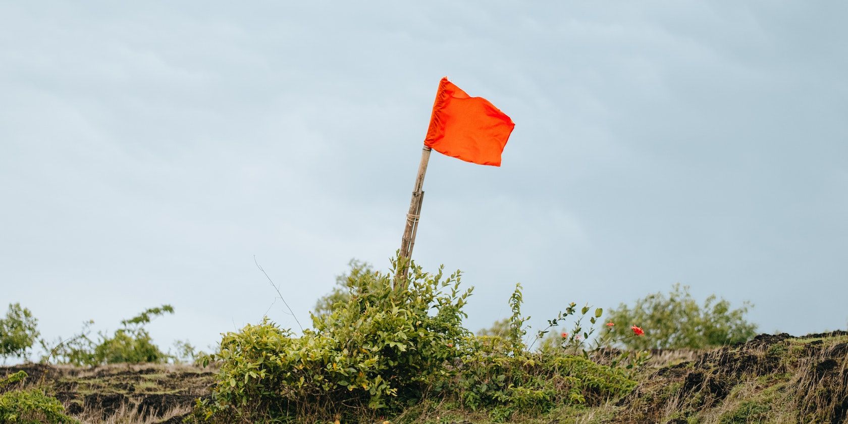 /vi/images/a-red-flag-flies-above-an-empty-field.jpg