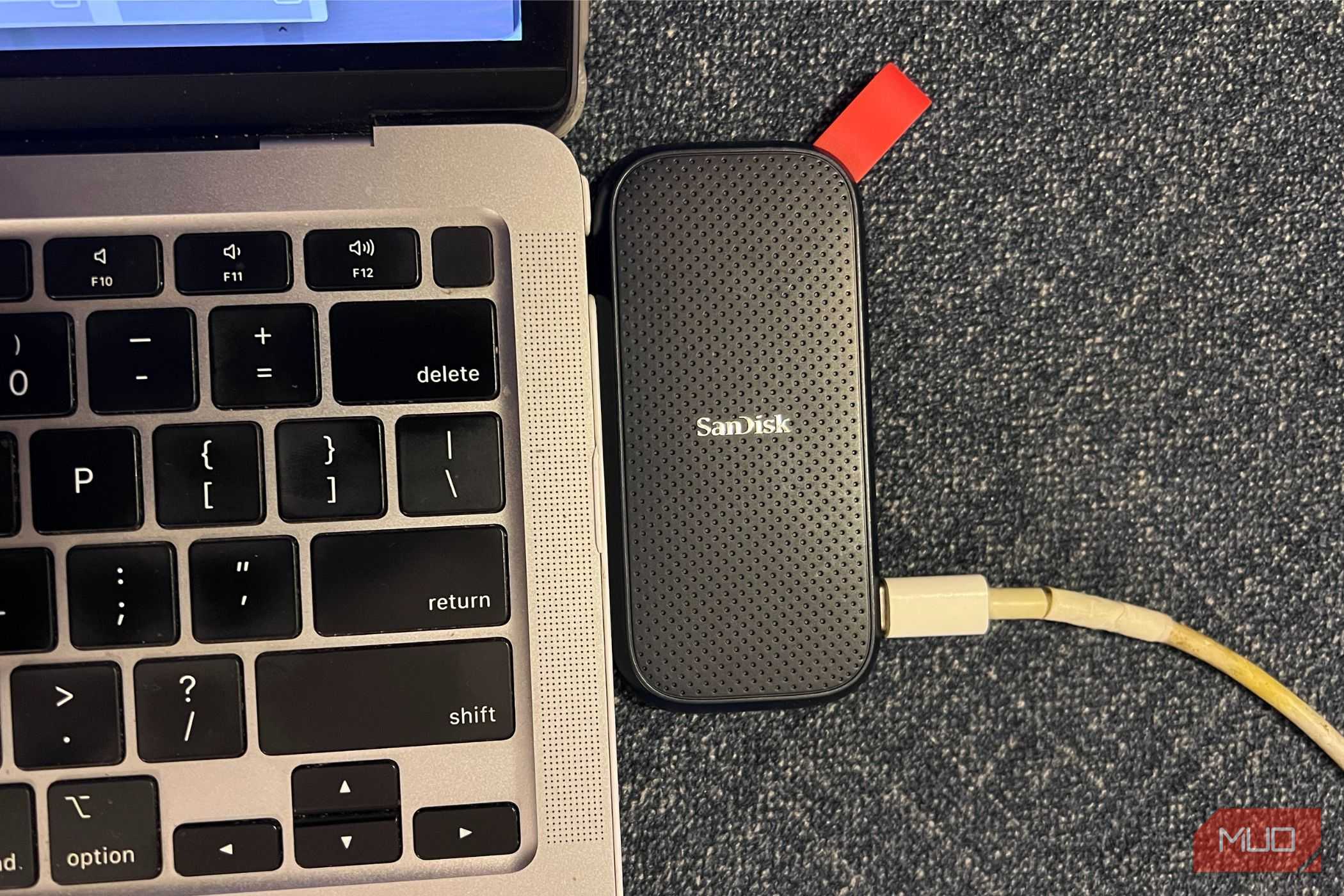 SanDisk ssd가 macbook 키보드 옆에 놓여 "삭제" 키가 강조됨